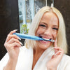 Woman with Power LED bleaching sonic toothbrush from Diamond Smile in her mouth in the bathroom