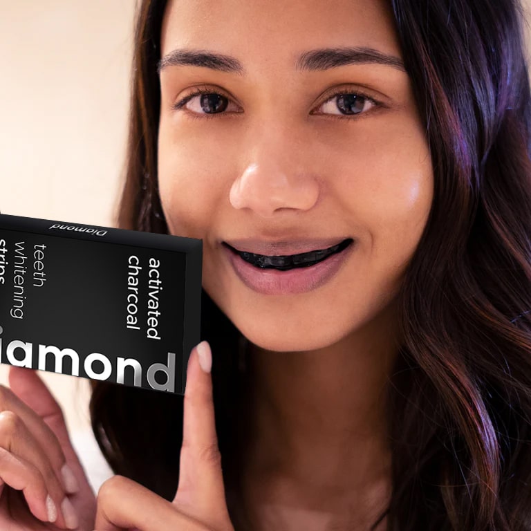 Woman with activated charcoal tooth whitening strips for teeth whitening at home