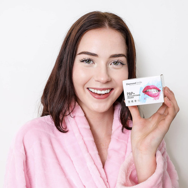 Woman holding Diamond Smile PAP+ Teeth Whitening Powder for brushing her teeth