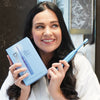 Woman with Power LED Bleaching sonic toothbrush from Diamond Smile in her hand in the bathroom