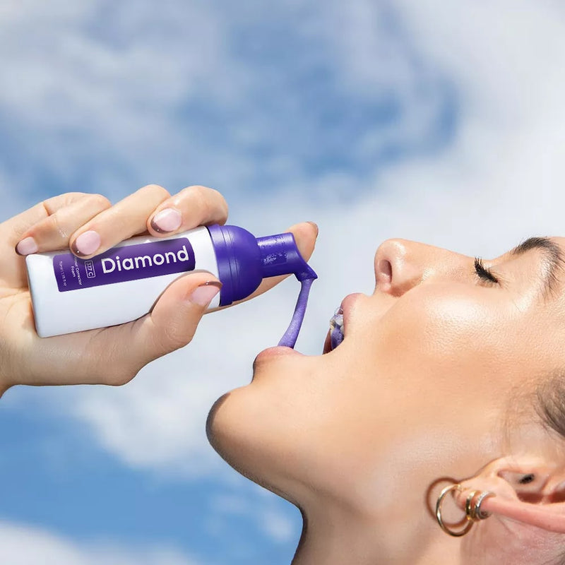 Woman with Diamond Smile purple tooth whitening color correction foam in hand