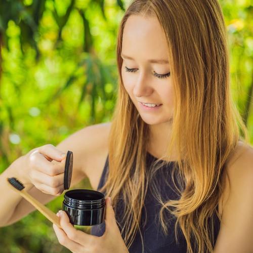 Woman with toothbrush and Diamond Smile tooth whitening activated charcoal powder Coco Powder